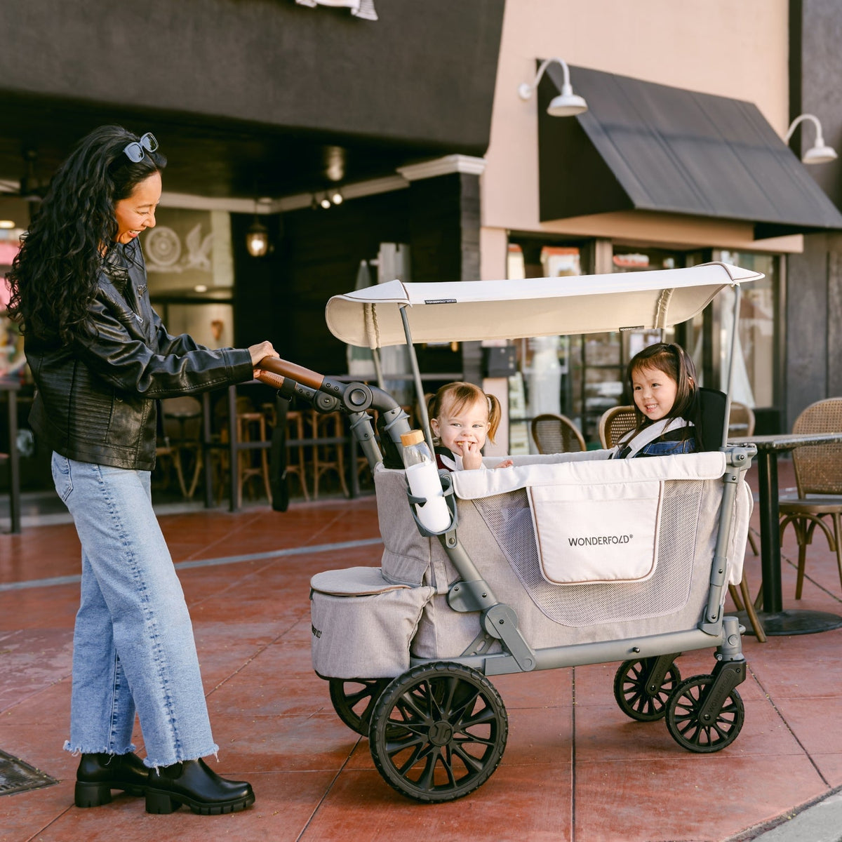 Woman pushing a stroller with two children in an outdoor setting